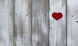 Red heart hanging on white fence