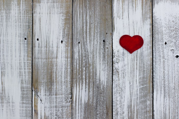 Red heart hanging on white fence