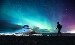 Northern lights in Mount Kirkjufell Iceland with a man passing by