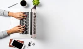 Female hands working on modern laptop. Office desktop on white background