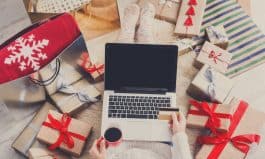 Woman makes christmas shopping online with laptop, above view