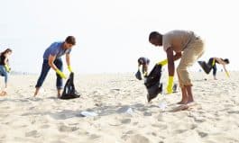 Group Of Volunteers Tidying Up Rubbish On Beach