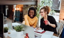 Two Businesswomen Working On Computer In Office