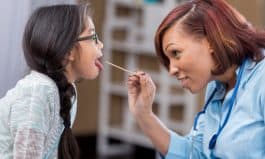 Confident African American pediatrician examines young Filipino patient