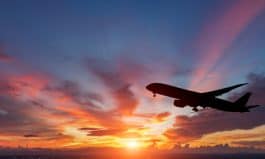 The silhouette of a passenger plane flying in sunset.