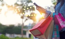 Woman using smartphone with shopping bag in hands