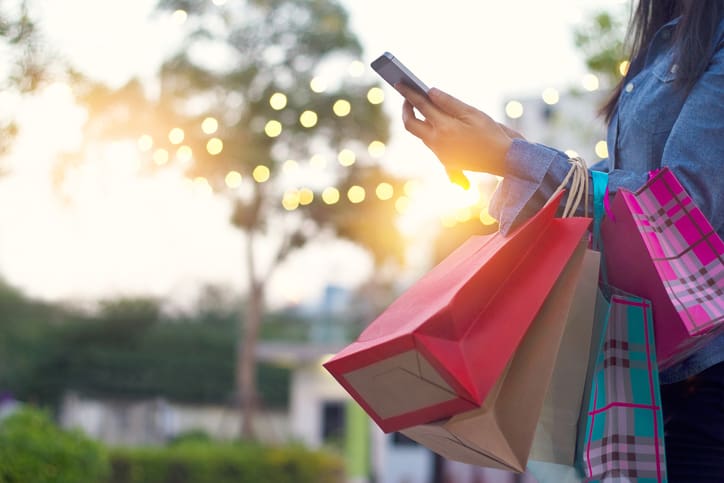 Woman using smartphone with shopping bag in hands