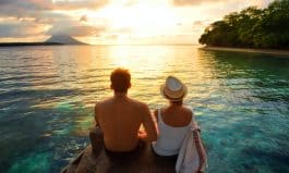 Happy couple on the pier on background colorful sunset