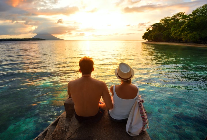 Happy couple on the pier on background colorful sunset